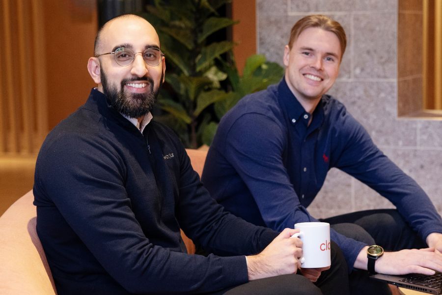 To kollegaer som sitter og smiler i et møterom hos Cloudworks